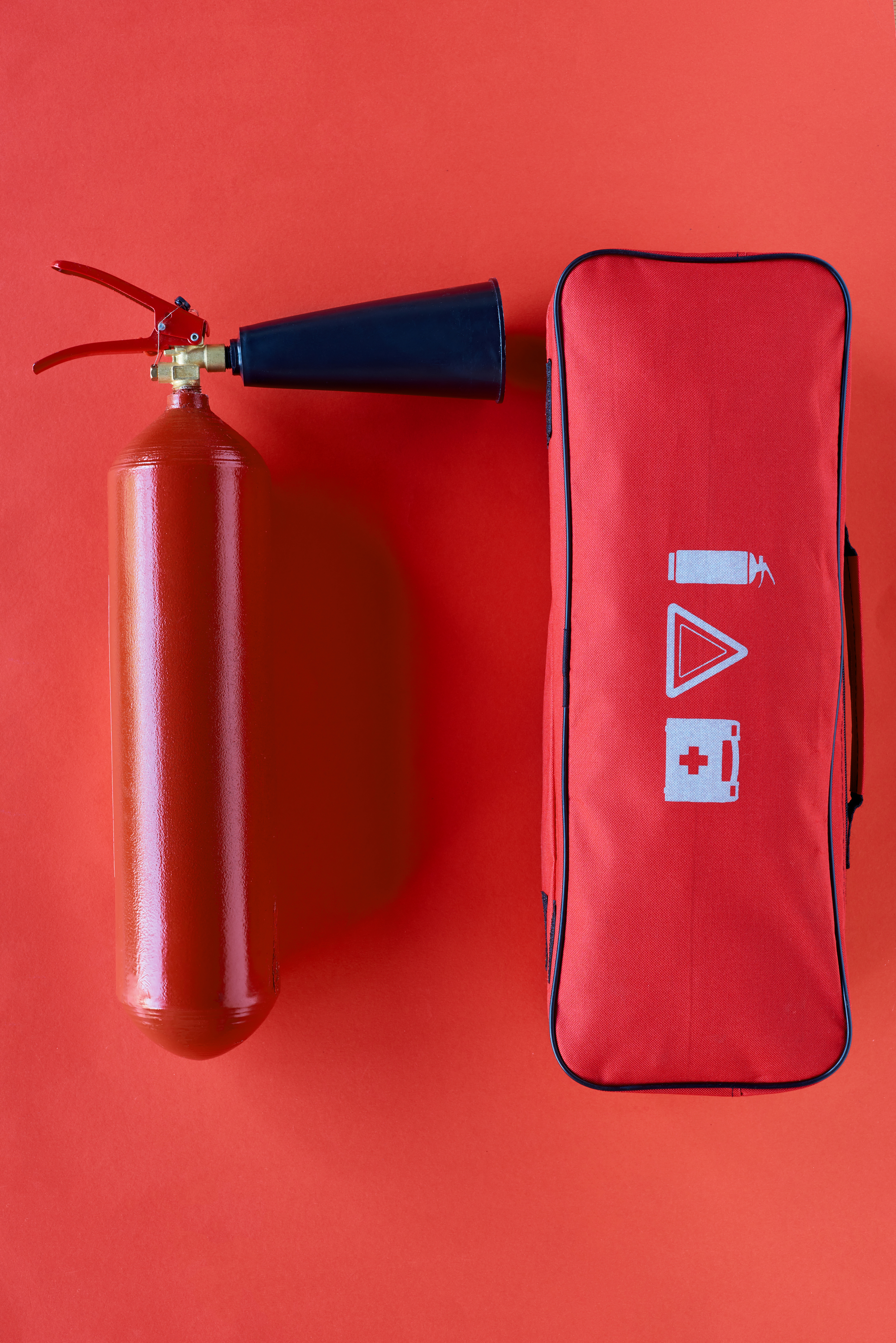 top view of fire extinguisher and automotive handbag on red background